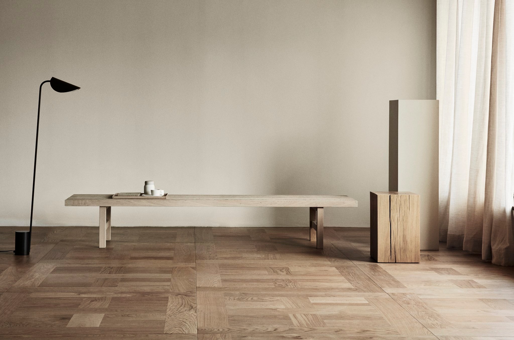 Minimalist interior with a long wooden table against a plain wall.